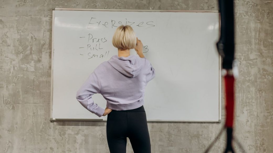 Person planning a weekly workout routine at the gym