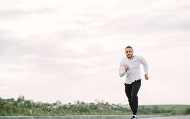 Adult man running on an empty road in casual sportswear, showcasing fitness and healthy lifestyle.