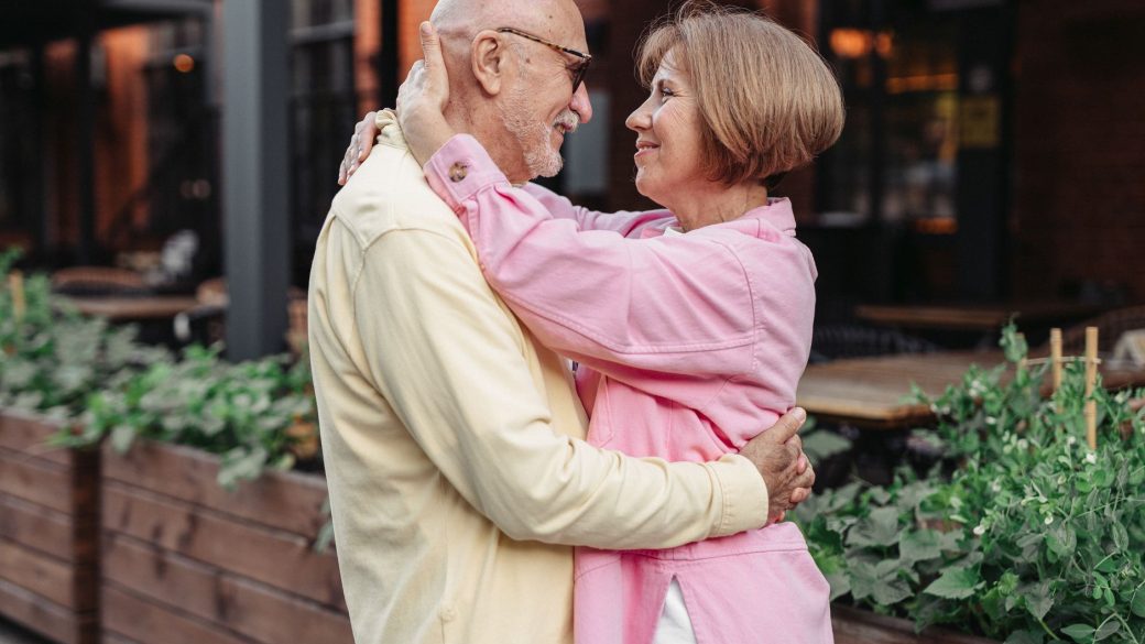 Elderly couple lovingly embracing outdoors, showcasing happiness and togetherness.