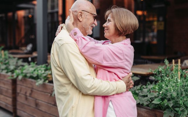 Elderly couple lovingly embracing outdoors, showcasing happiness and togetherness.