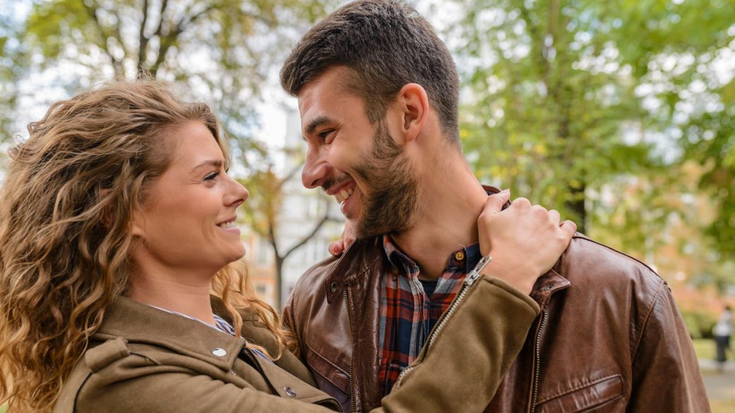 Happy couple enjoying a romantic moment outdoors, embracing and smiling at each other.