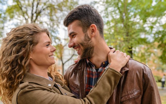 Happy couple enjoying a romantic moment outdoors, embracing and smiling at each other.