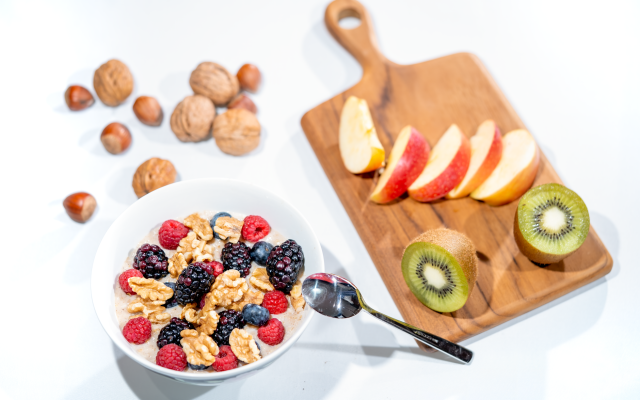 A nutritious breakfast bowl featuring fresh berries and walnuts, served with sliced fruit and kiwi.