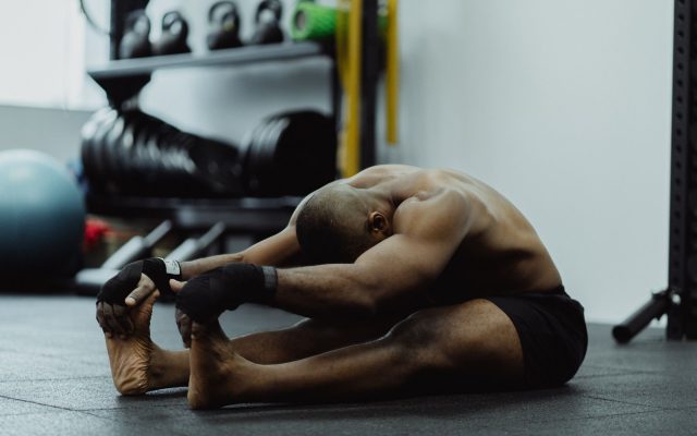 Man doing seated stretch in gym, emphasizing fitness and flexibility training.