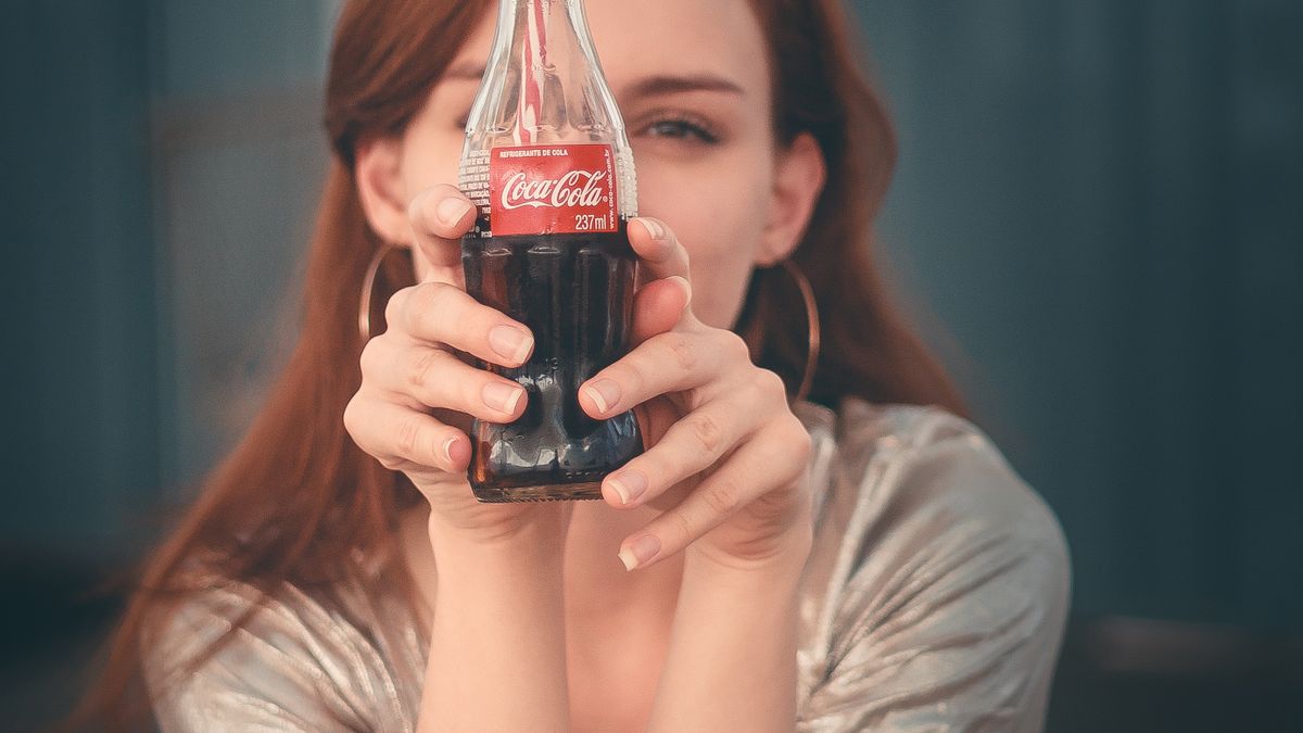 Woman holding a bottled soda, one of the biggest sources of added sugar