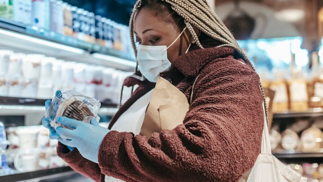 Woman reading a food label in a supermarket to check for added sugar