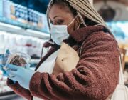 Woman reading a food label in a supermarket to check for added sugar