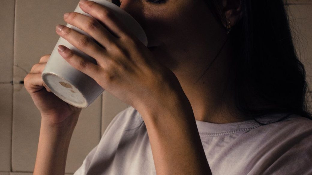 Woman holding a warm cup of coffee in the morning light