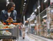Woman reading a food package label while grocery shopping