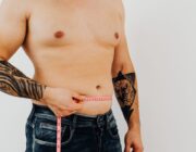 Man measuring his waist with a tape measure to track belly fat