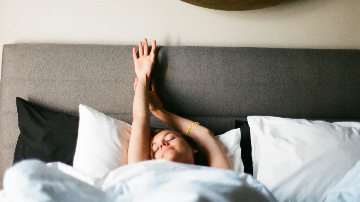 A person stretching in bed in the morning light after waking