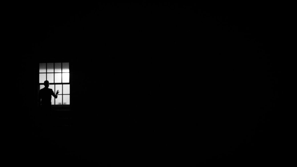 Person looking pensively out a window, coping with loneliness