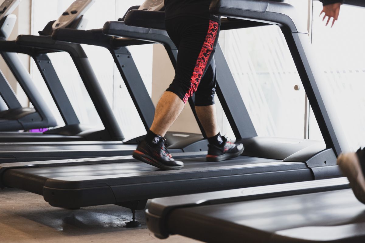 Person walking on a treadmill at an incline in the gym