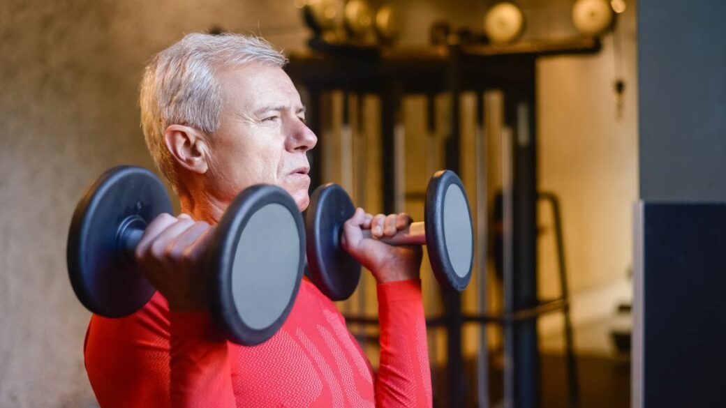 Fit older man lifting dumbbells to support men's health after 50