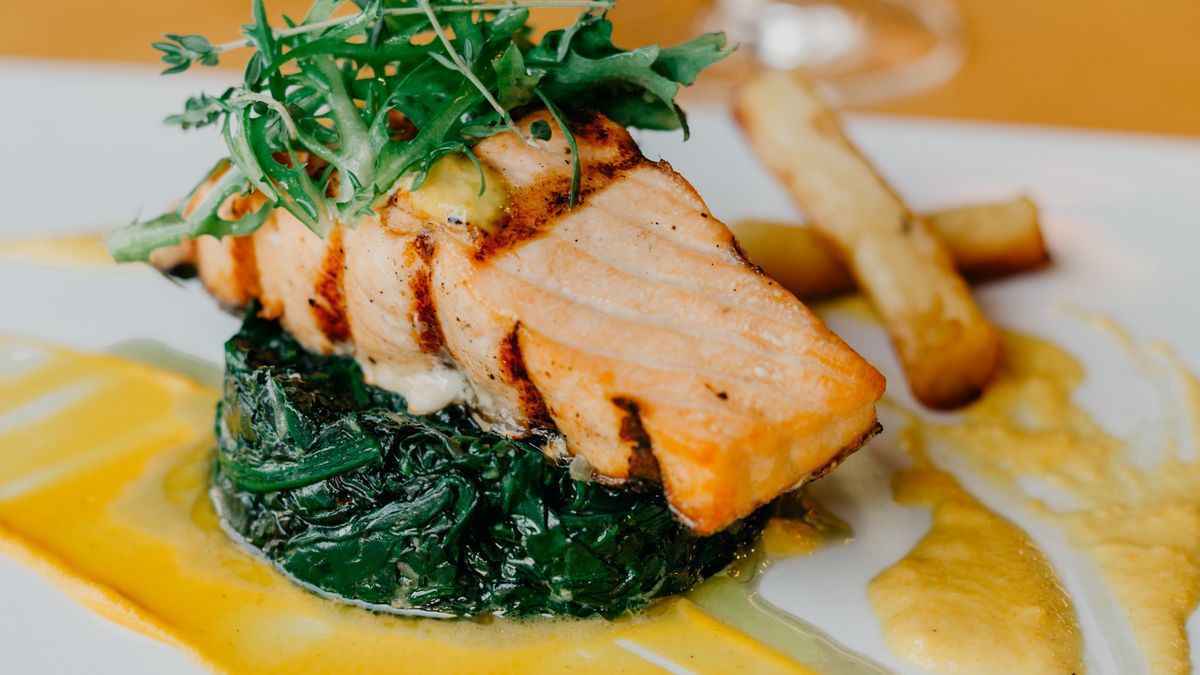 A cooked salmon fillet with spinach, a source of omega-3 fatty acids