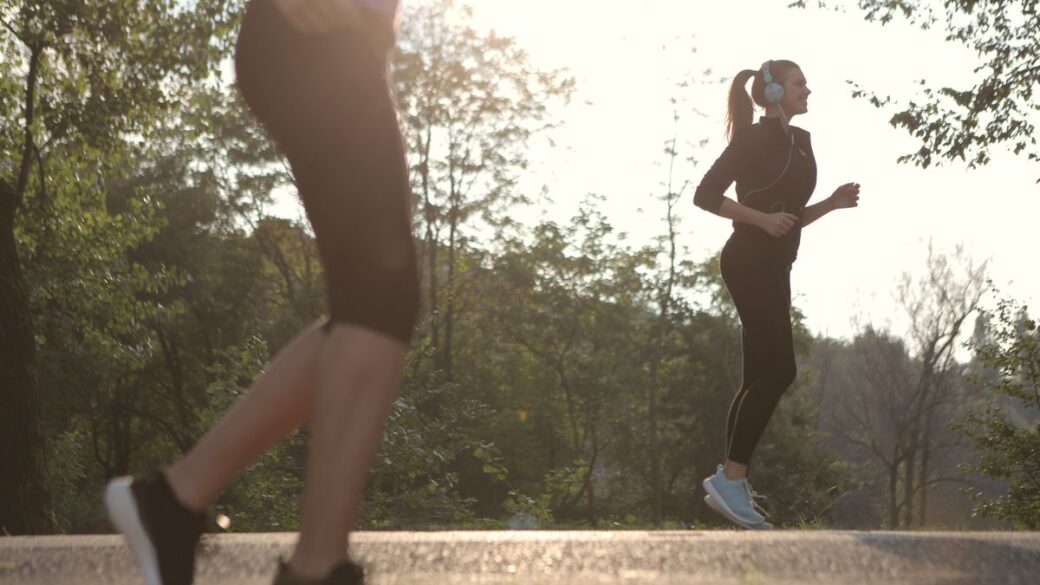 Two women walking briskly for exercise in a sunny park