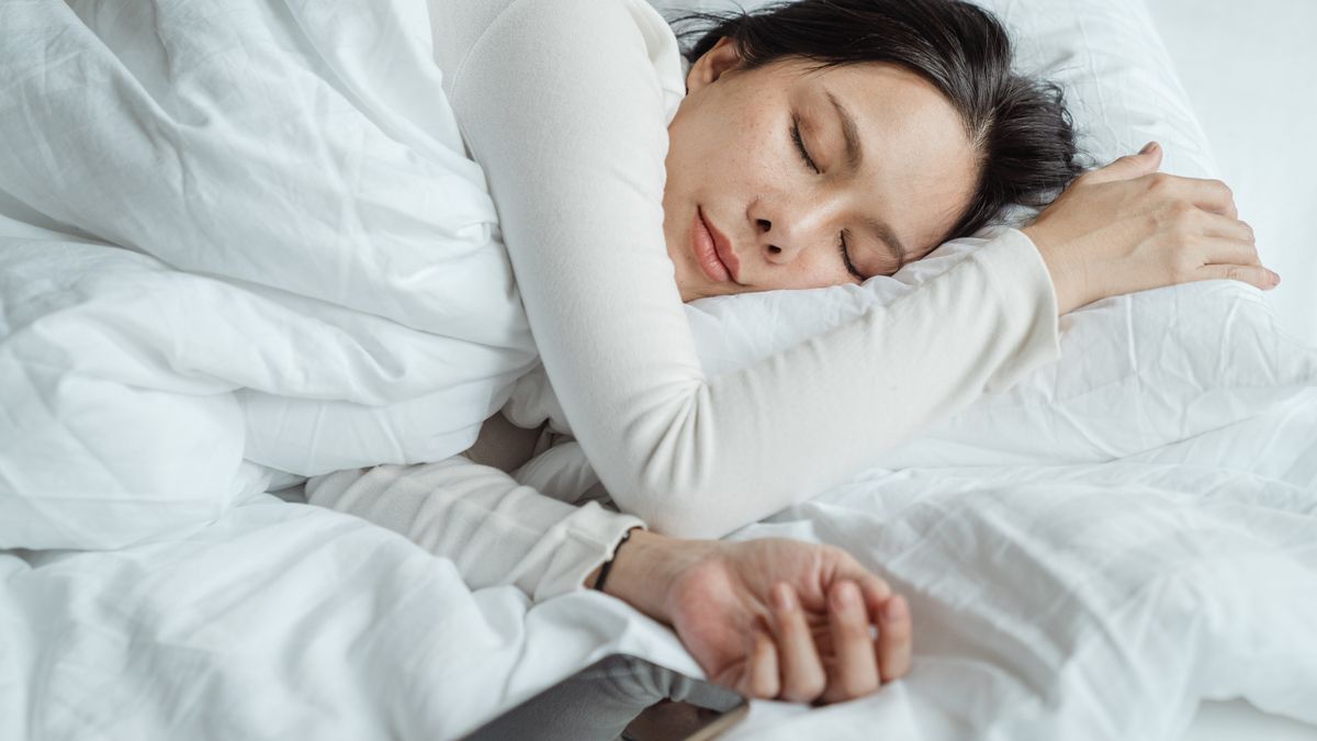 Woman sleeping in a cool dark bedroom set up for good sleep