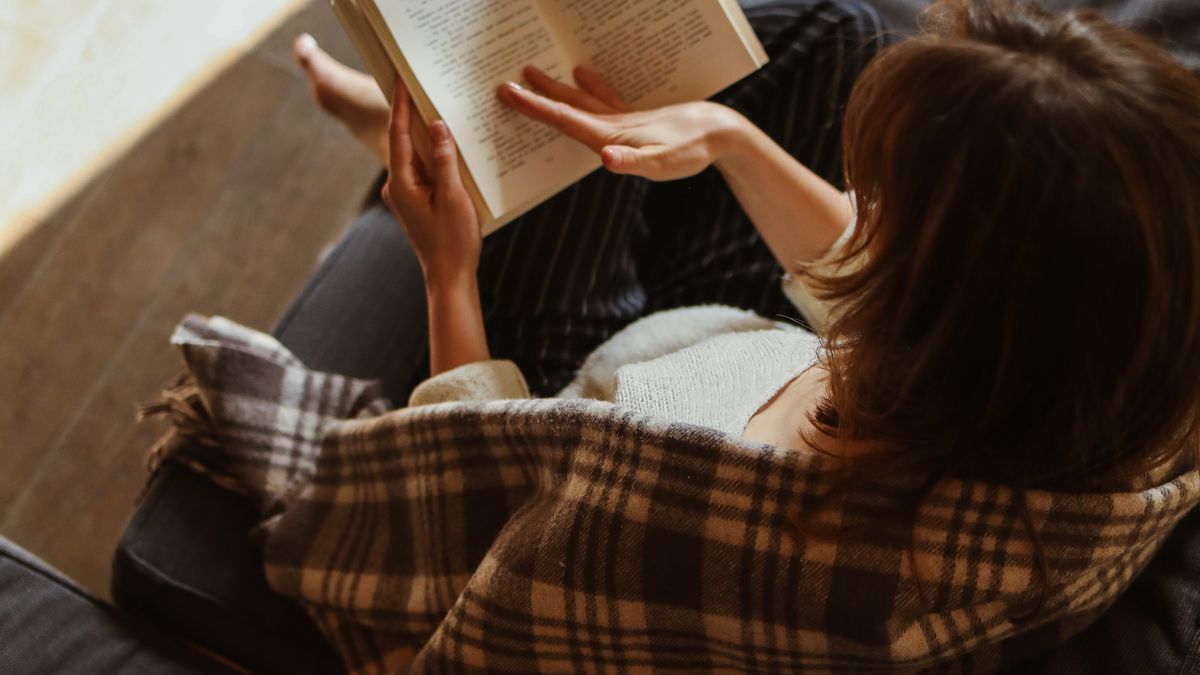 Woman relaxing with a book instead of social media, a phone-free habit that supports mental health