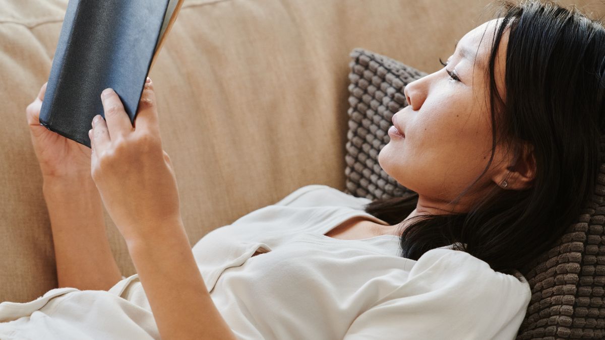 Woman winding down with a book in the evening, a dim-light routine that protects natural melatonin