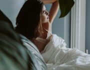 Woman waking up in a bedroom in morning light, illustrating chronotype and sleep timing