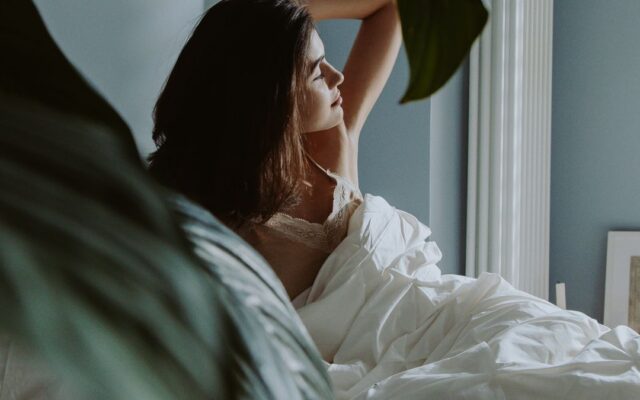 Woman waking up in a bedroom in morning light, illustrating chronotype and sleep timing