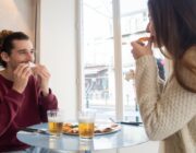 Man and woman sharing pizza in a restaurant, enjoying a planned cheat meal