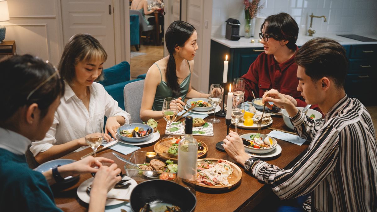 Friends having a relaxed conversation over dinner at a table together