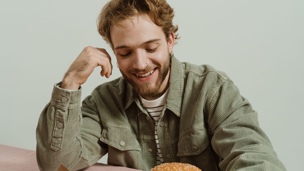 Man looking at a large burger on a table before eating a cheat meal
