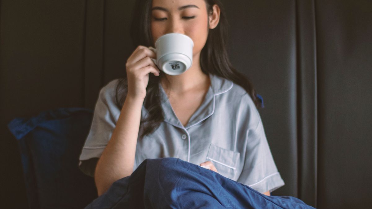 Woman drinking coffee in bed after a poor night of sleep caused by late caffeine