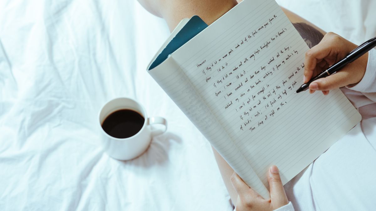 Woman writing a worry list in a notebook on her bed before sleep to manage stress