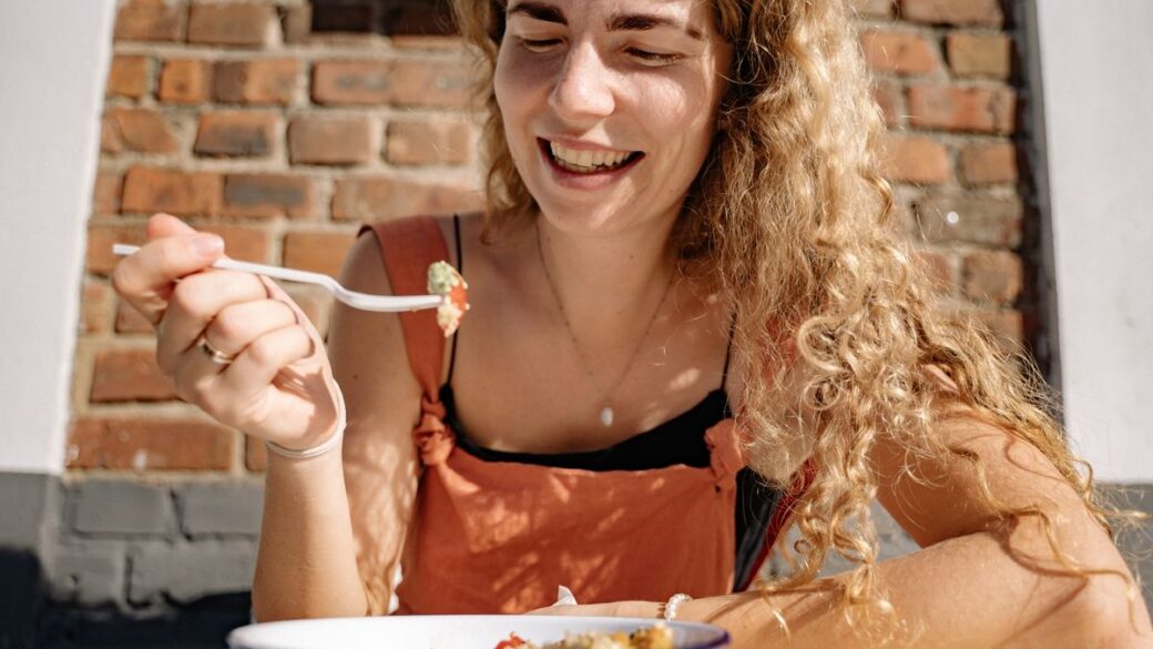 Smiling woman eating a healthy breakfast at a sunny table
