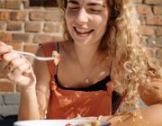 Smiling woman eating a healthy breakfast at a sunny table