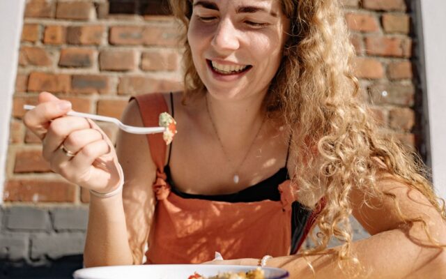 Smiling woman eating a healthy breakfast at a sunny table
