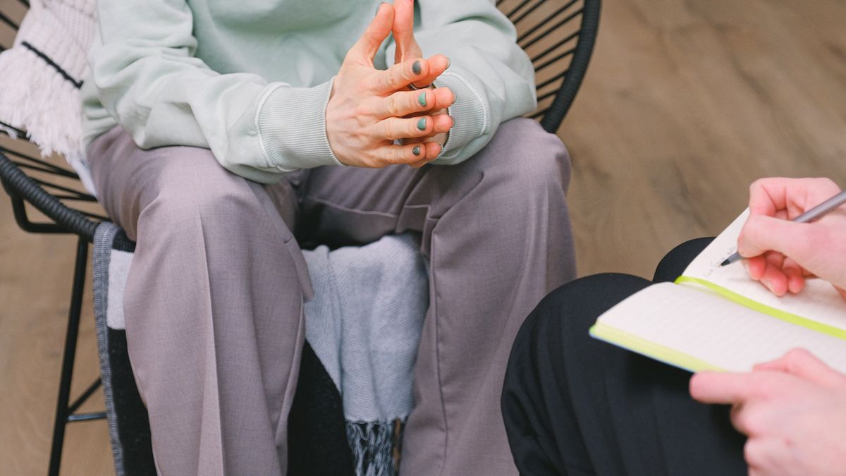 Therapist taking notes in a notebook during a counseling session with a client