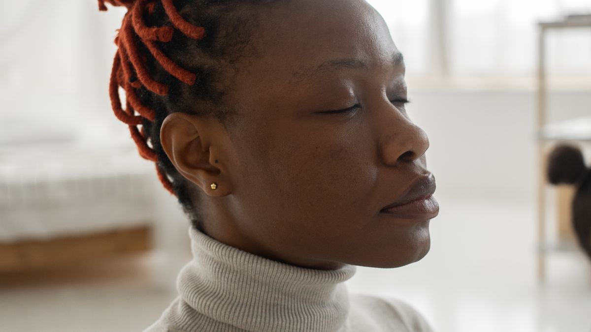 Calm woman practicing slow breathing and relaxation at home to reduce stress before bed