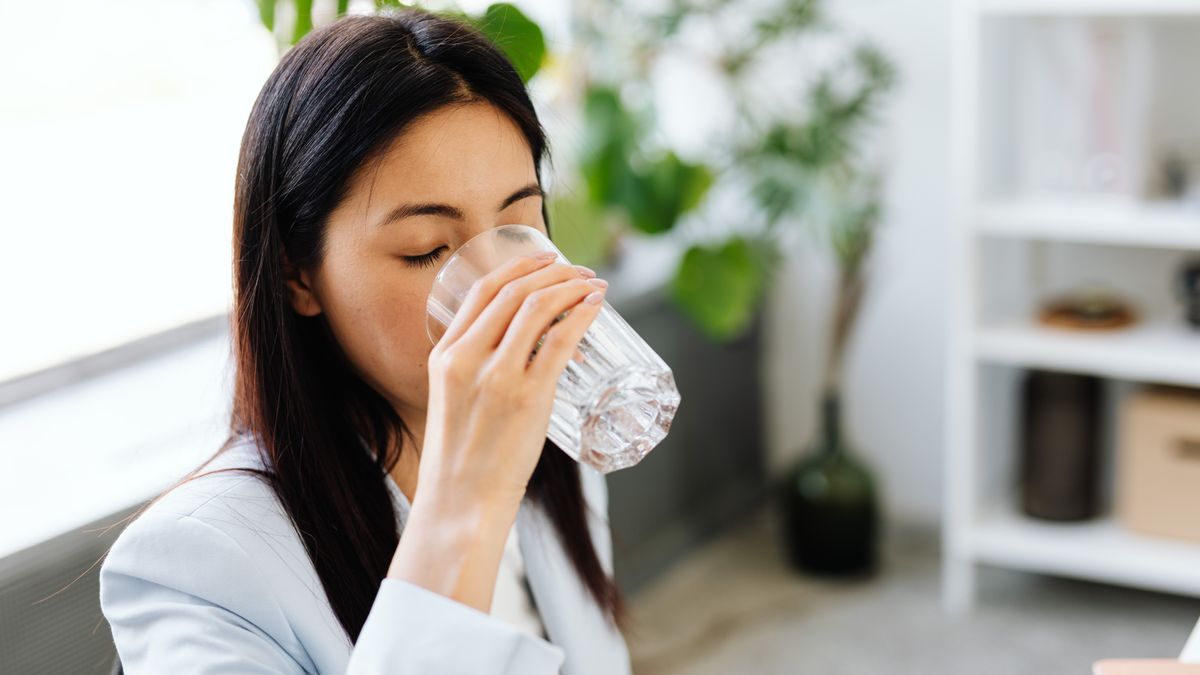 Close-up of a woman drinking a glass of water instead of caloric drinks