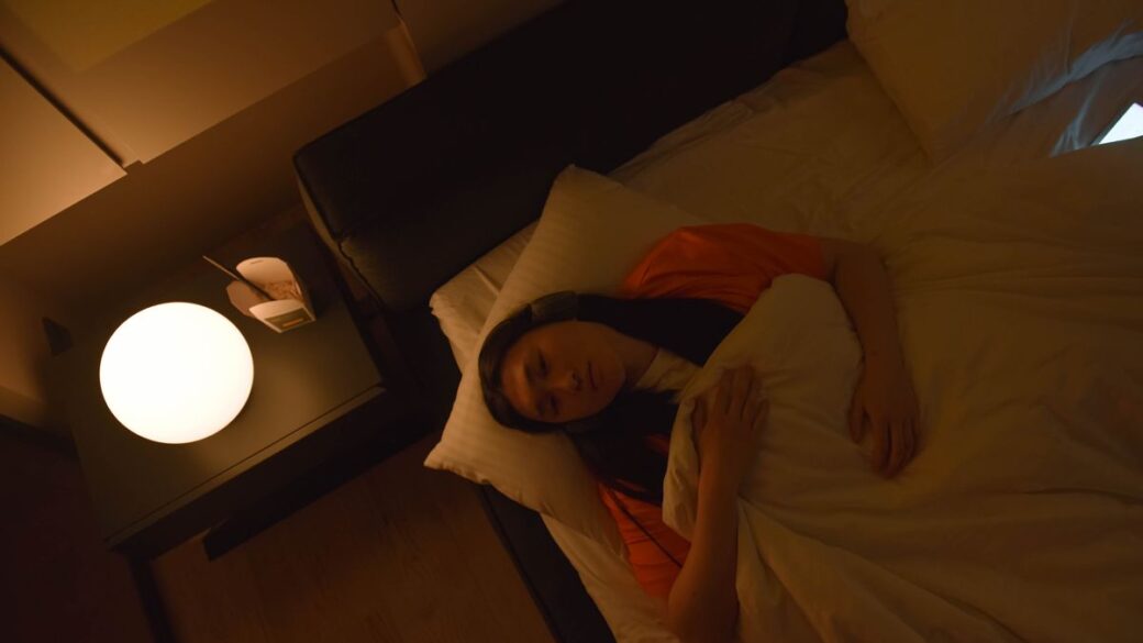 Woman lying awake in bed at night, unable to sleep because of stress