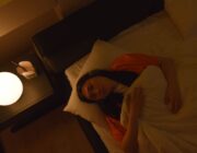 Woman lying awake in bed at night, unable to sleep because of stress