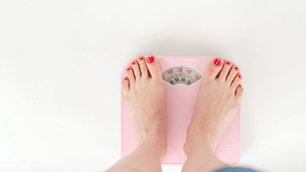 Woman standing on a bathroom scale, illustrating set point theory and weight regulation