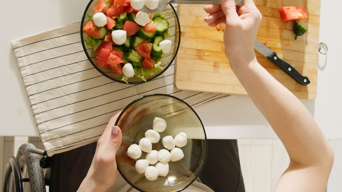 Person preparing a healthy salad in a kitchen while managing weight loss