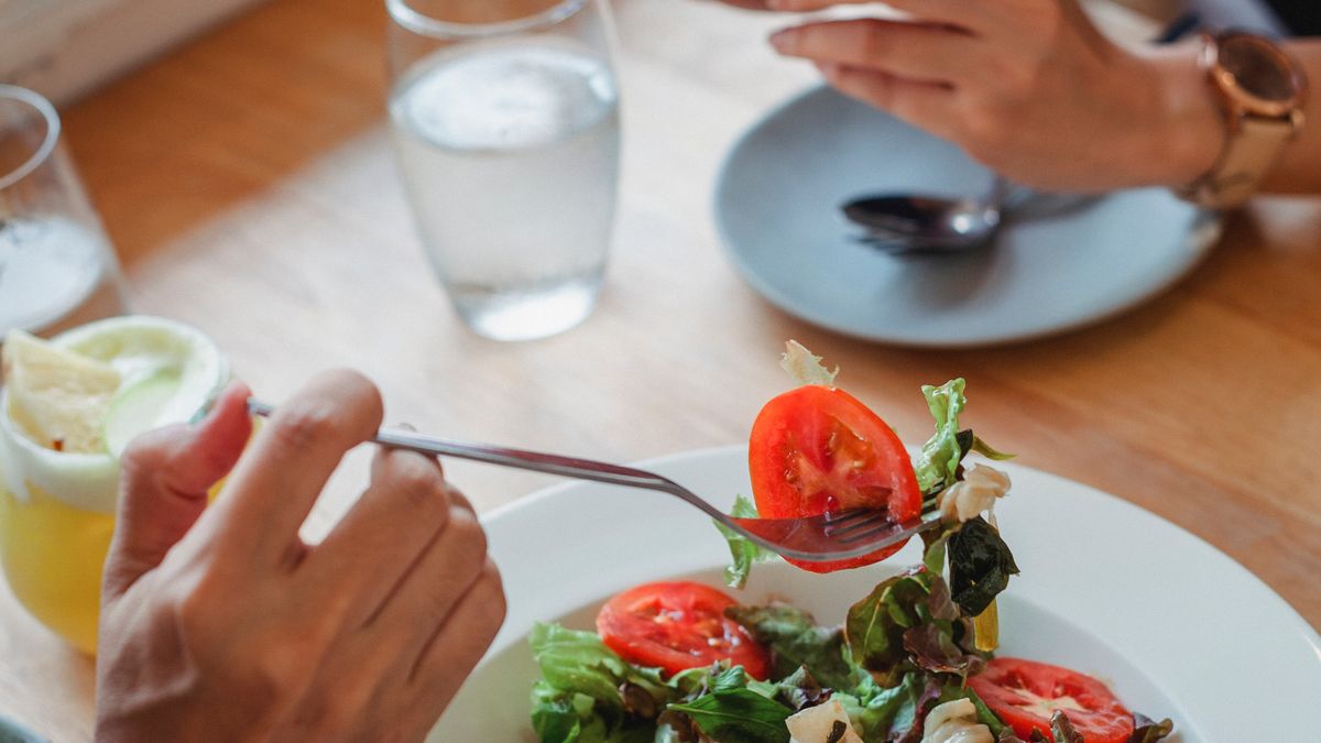 Person eating a salad portion from a plate, controlling portion sizes at a meal