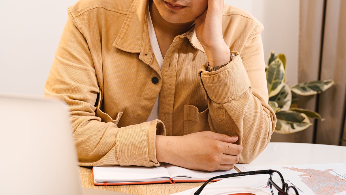 Man procrastinating at his laptop, feeling frustrated by an unstarted task