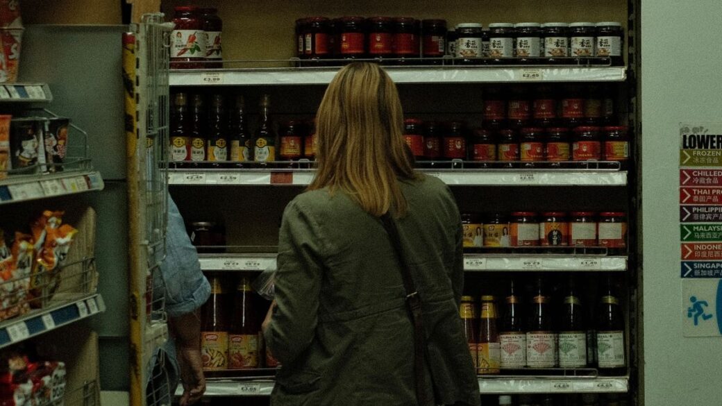 Woman reading a food package label in a supermarket aisle