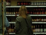 Woman reading a food package label in a supermarket aisle