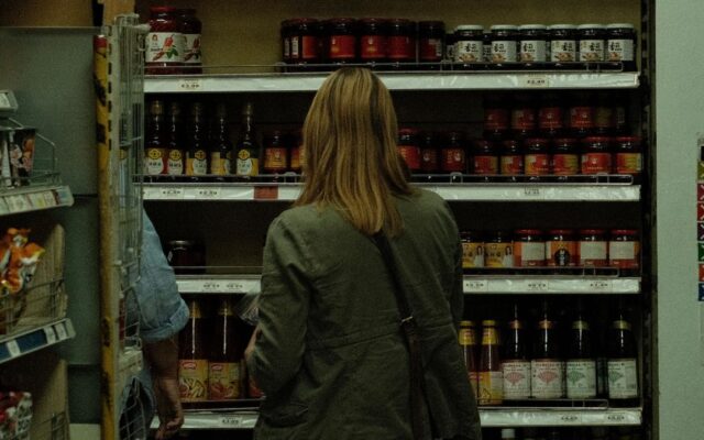Woman reading a food package label in a supermarket aisle