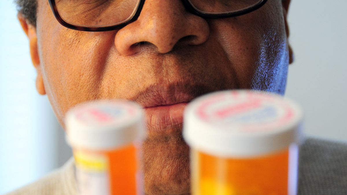 Man reading the labels on two prescription pill bottles at home