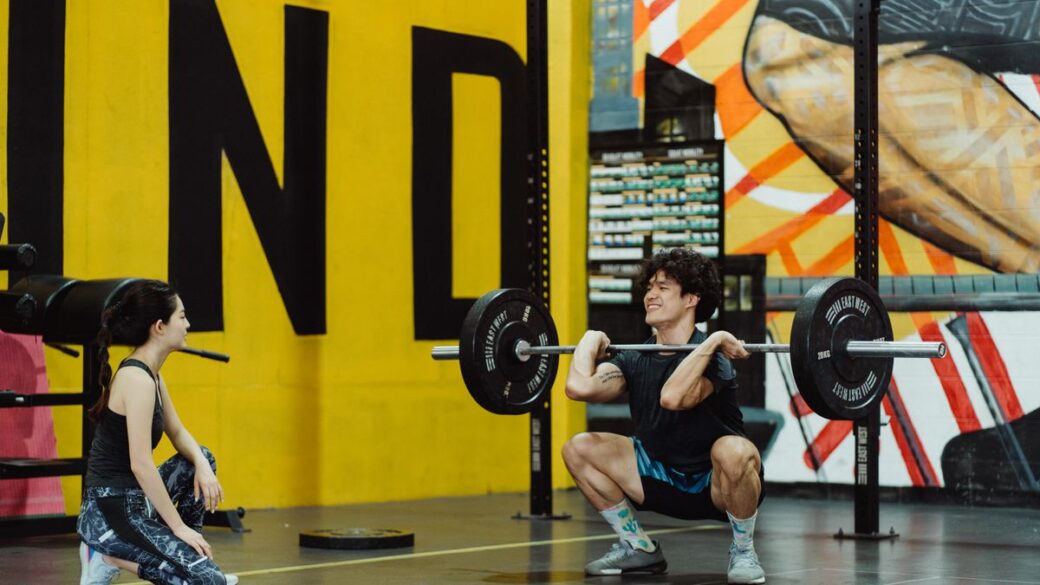 Man holding a loaded barbell across his shoulders, demonstrating progressive overload in strength training
