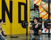 Man holding a loaded barbell across his shoulders, demonstrating progressive overload in strength training