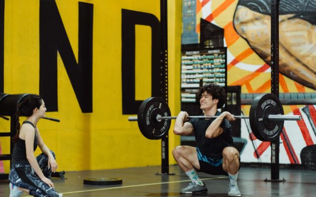 Man holding a loaded barbell across his shoulders, demonstrating progressive overload in strength training