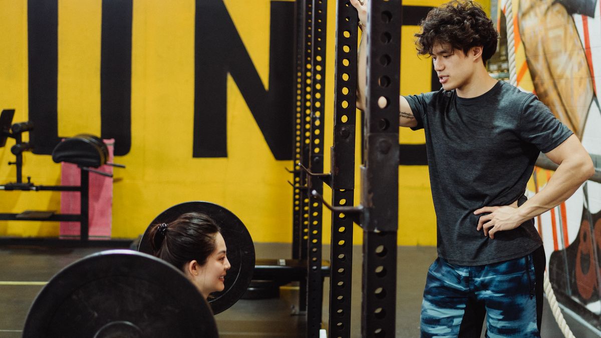 Woman performing a controlled barbell squat with good form in a gym
